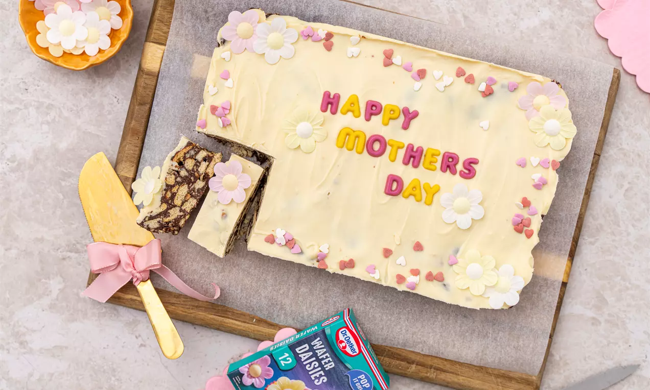 A chocolate biscuit slab covered in white chocolate and decorated with letters saying 'Happy Mothers Day'