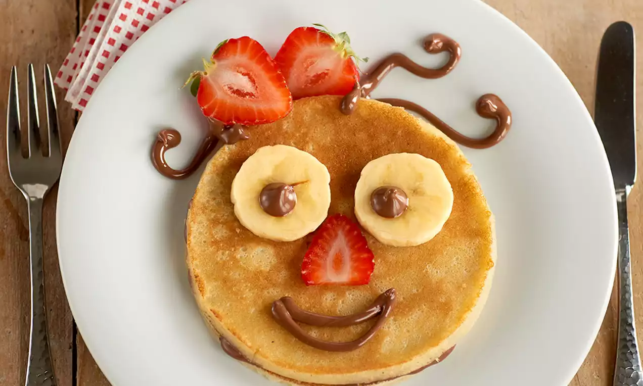 Base dorada con textura suave, decorada con fresas cortadas en abanico y líneas curvas de crema de chocolate sobre un plato blanco