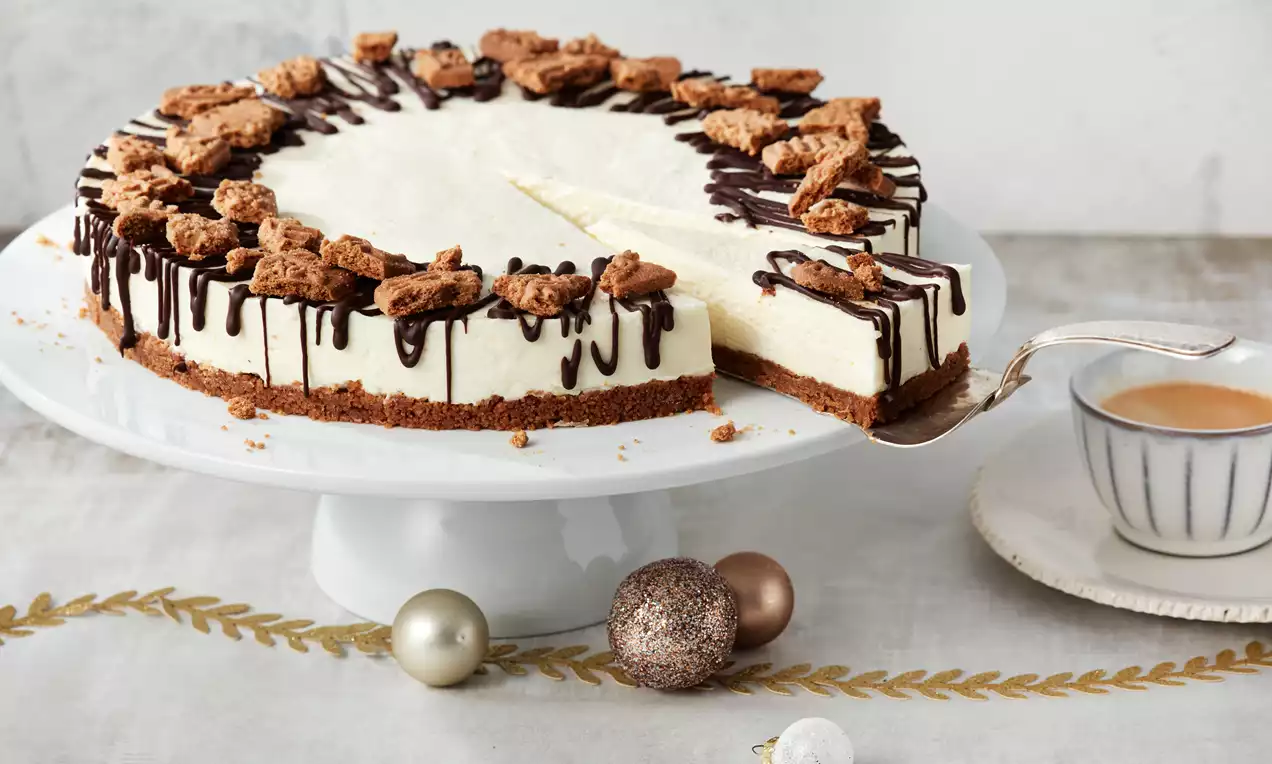 Spekulatius-Cheesecake mit cremiger weißer Frischkäsefüllung auf goldbraunem Spekulatiusboden, garniert mit Bröseln und Zimt