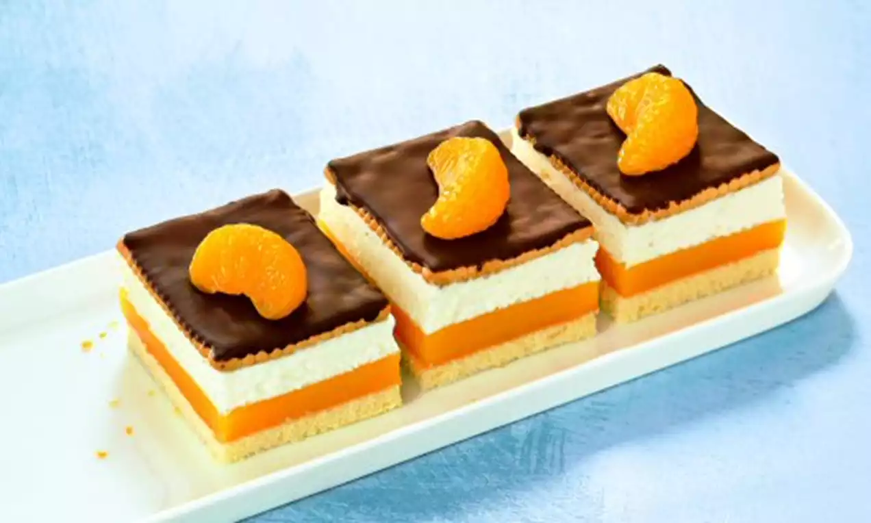 Kuchenstücke mit Schichten aus hellem Biskuit, orangefarbener Creme, weißer Füllung, Schokoglasur und einer Mandarinen-Spalte oben