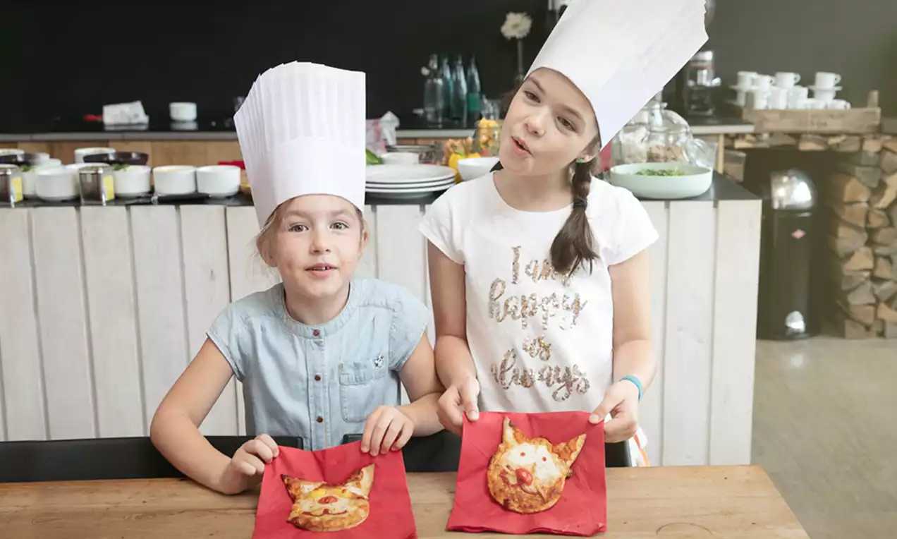 Deux pizzas Margherita individuelles en pâte dorée, garnies de fromage fondu et de tomates, présentées sur des serviettes rouges
