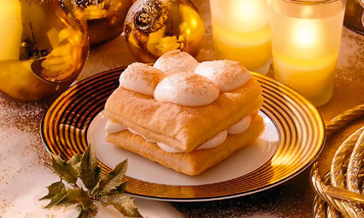 Torta Sherry e cannella con strati di pasta dorata friabile, crema soffice bianca e spolverata di cannella su un piatto dorato