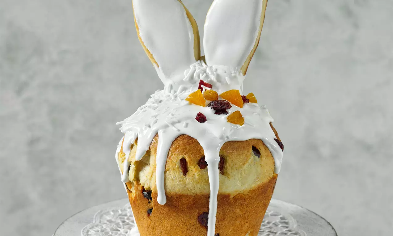 Mini mazanec zlatohnedý s bielou polevou stekajúcou po stranách, ozdobený kúskami sušeného ovocia a zajačími ušami na vrchu