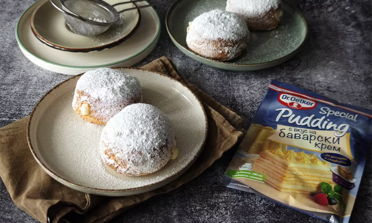 Златисти кръгли понички с мека повърхност, поръсени с бял слой пудра захар, от които се подава крем, подредени върху чинии и кърпа