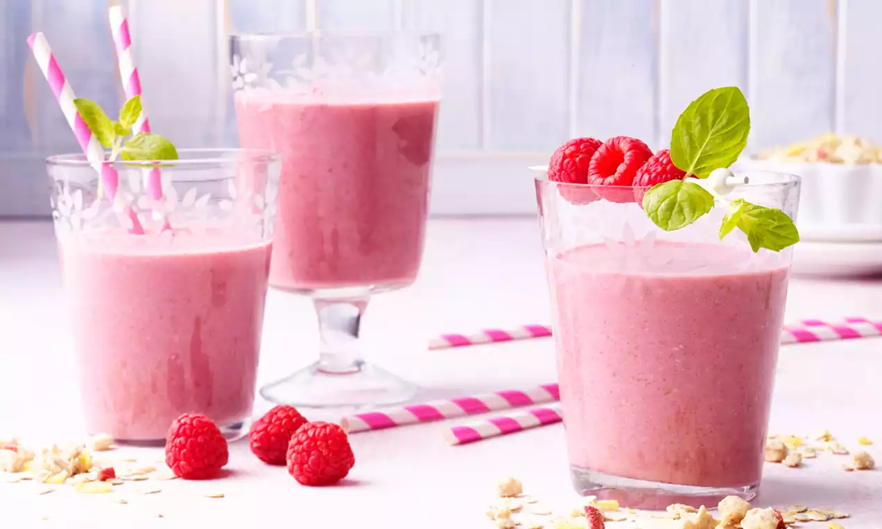 Pembe meyveli içeceklerin üç bardağa doldurulduğu, böğürtlenler ve nane yapraklarıyla süslendiği, renkli pipetlerle tamamlanmış canlı bir sunum