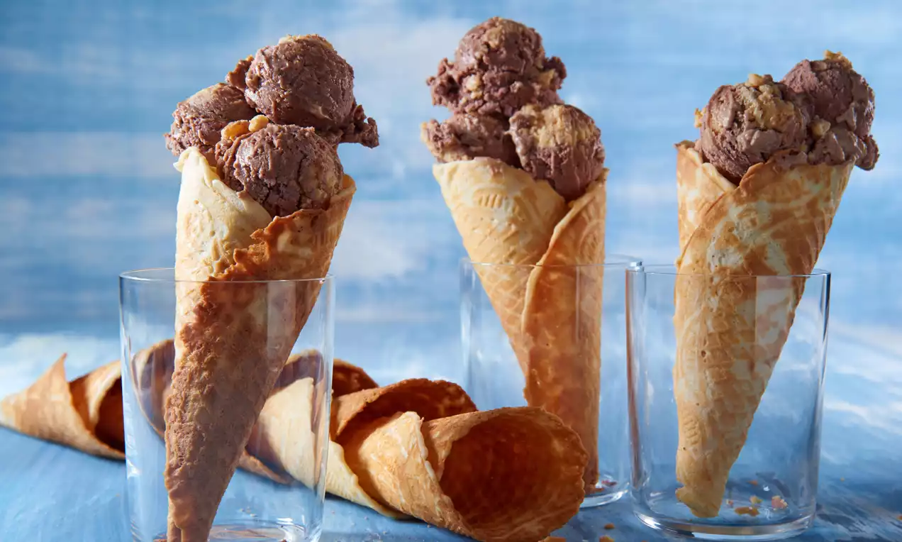 Glaces chocolat-caramel crémeuses aux tons bruns dorés, servies dans des cornets gaufrette croustillants disposés dans des verres transparents