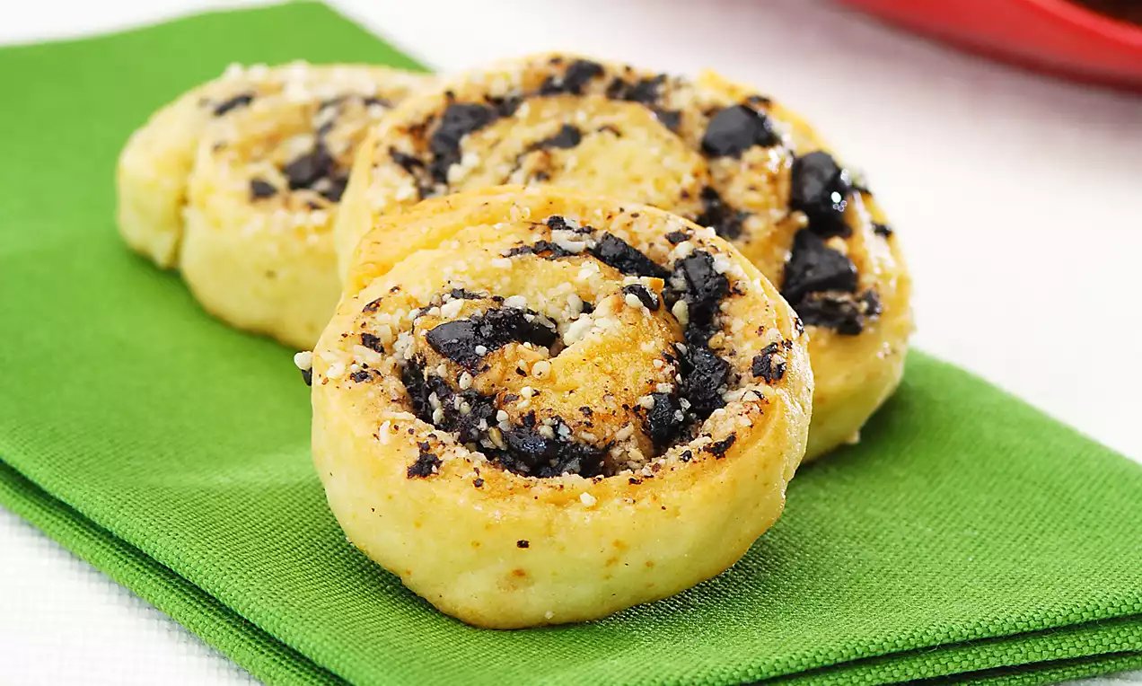 Altın sarısı kıvamında, içi yoğun çikolata parçaları dolu rulo kurabiyeler yeşil bir peçete üzerinde düzenlenmiş şekilde sunulmuş