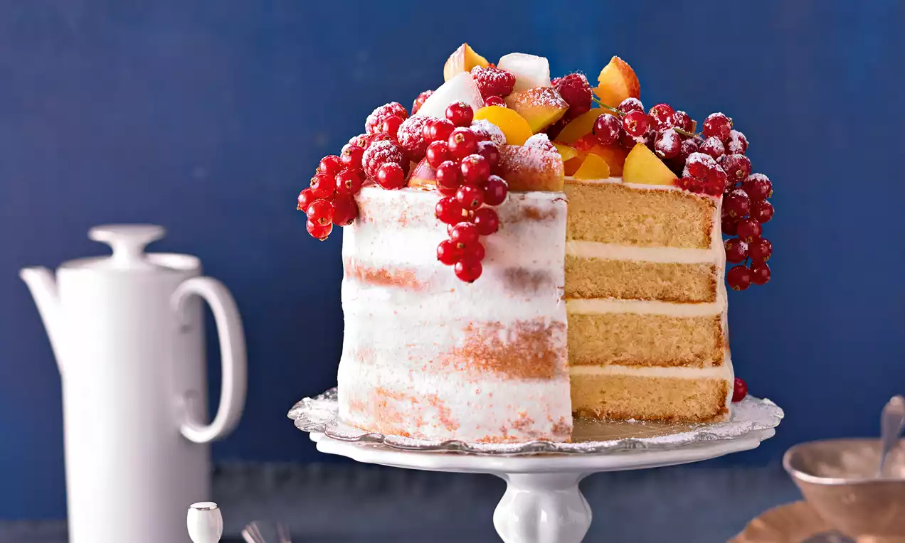 Wiener Tortenboden mit hellgoldener, feinporiger Biskuitkrume auf Backpapier, eine herausgeschnittene Scheibe zeigt lockere, luftige Struktur