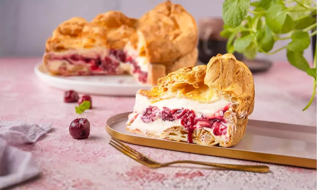 Fotografia przedstawia karpatkę z kremem śmietankowymi i wiśniami