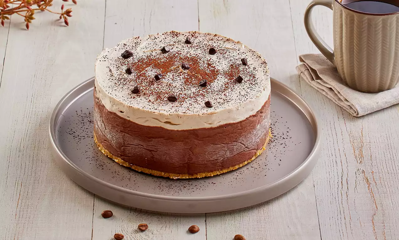 Kremalı kahverengi çikolata dolgu, altın sarısı bisküvi taban, üstü krema ve kahve çekirdeği taneleriyle bej tabakta sunulmuş