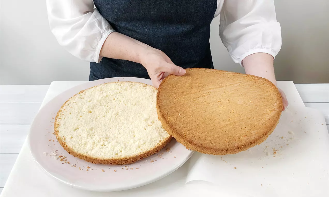 Кръгъл блат в светлозлатисто-кафяво, разрязан хоризонтално, с мека и гладка вътрешност, върху бяла чиния на светъл фон