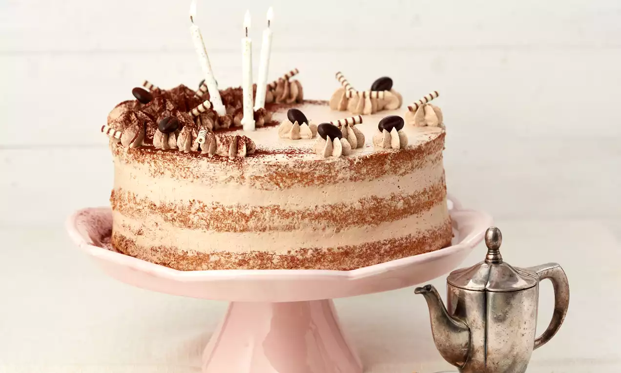 Biskuitboden mit goldbrauner, luftiger Krume, leicht bestäubt mit Puderzucker und garniert mit frischen roten Erdbeeren und Minzblättern