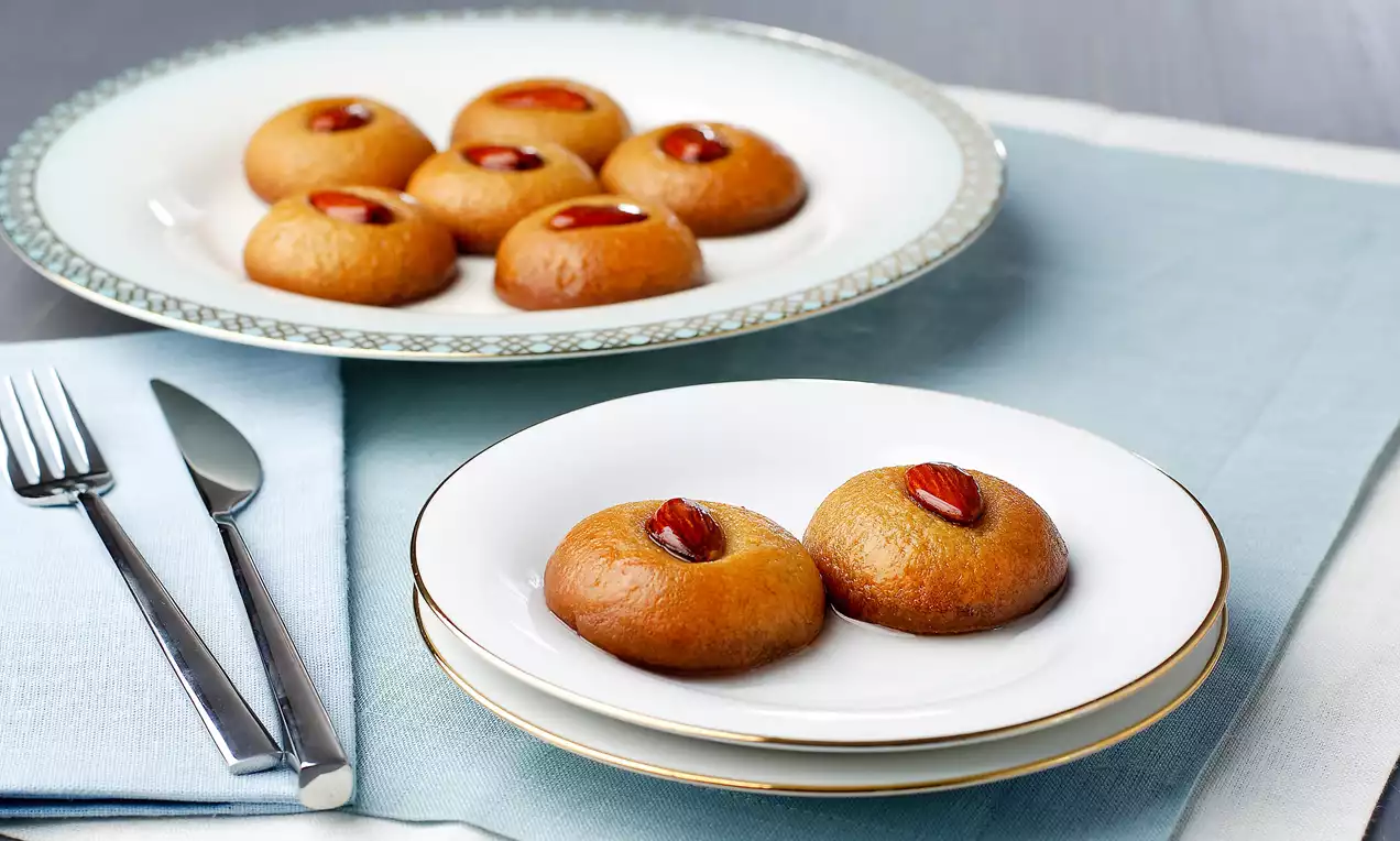 Altın rengi, parlak şerbetli şekerpareler, ortalarında birer bademle süslenmiş ve beyaz tabaklarda düzenli şekilde sunulmuş