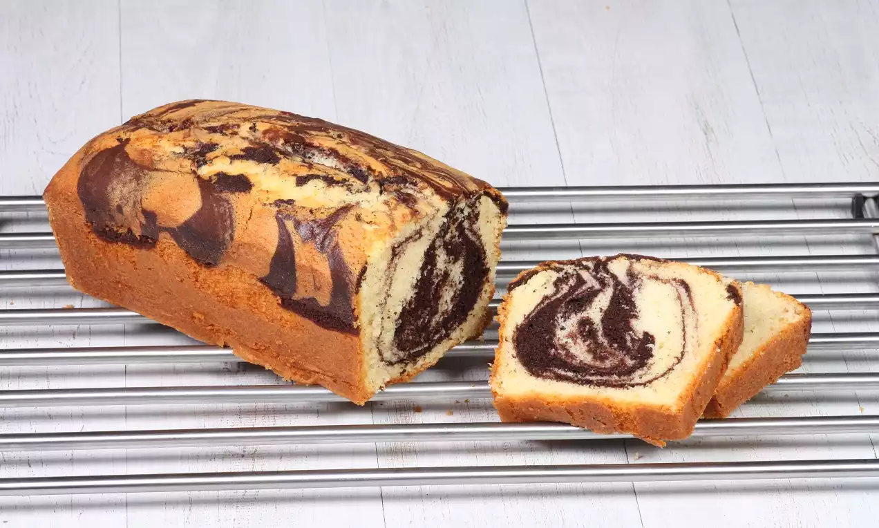 Kakaolu ve sade hamurun mermer deseni oluşturduğu dikdörtgen kek, metal ızgara üzerinde dilimlenmiş şekilde yerleştirilmiş