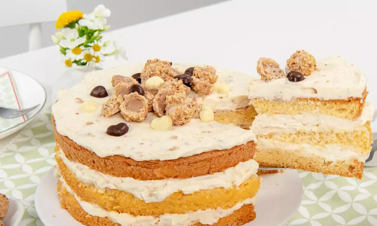 Mehrschichtige Giotto-Torte mit hellbraunem Biskuit und cremefarbener Füllung, oben verziert mit Pralinen und Schokoladendekor