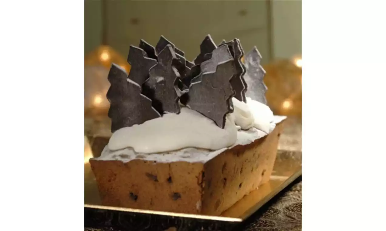 Rechthoekige kerstcake met lichte roomlaag, donkere chocoladekerstbomen bovenop, gepresenteerd op een goudkleurige schaal