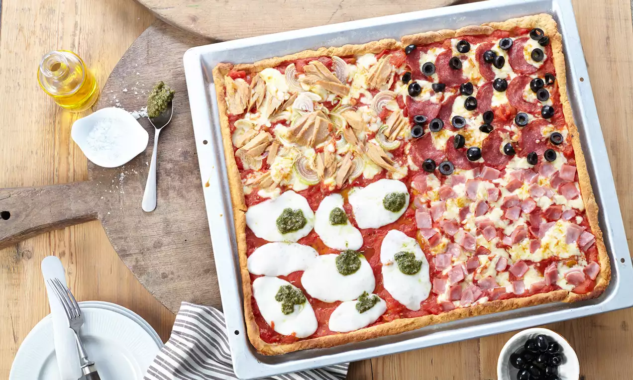 Quark-Öl-Teig als goldbrauner Obstkuchen mit glänzenden roten Beeren, Pfirsichscheiben und Puderzucker auf hellem Teller drapiert