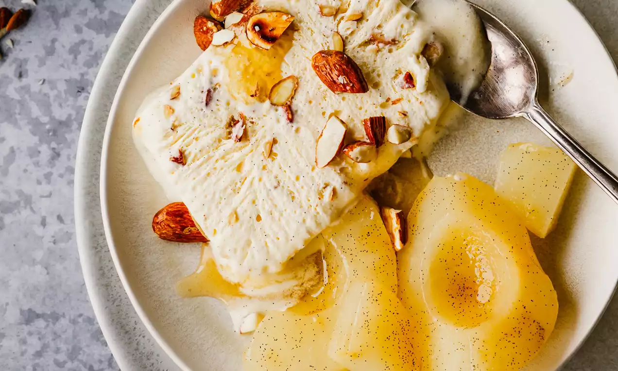 Picture - Creamy almond parfait with a rectangular shape, topped with golden honey and crunchy almond pieces, served alongside soft vanilla-poached pear slices on a white plate