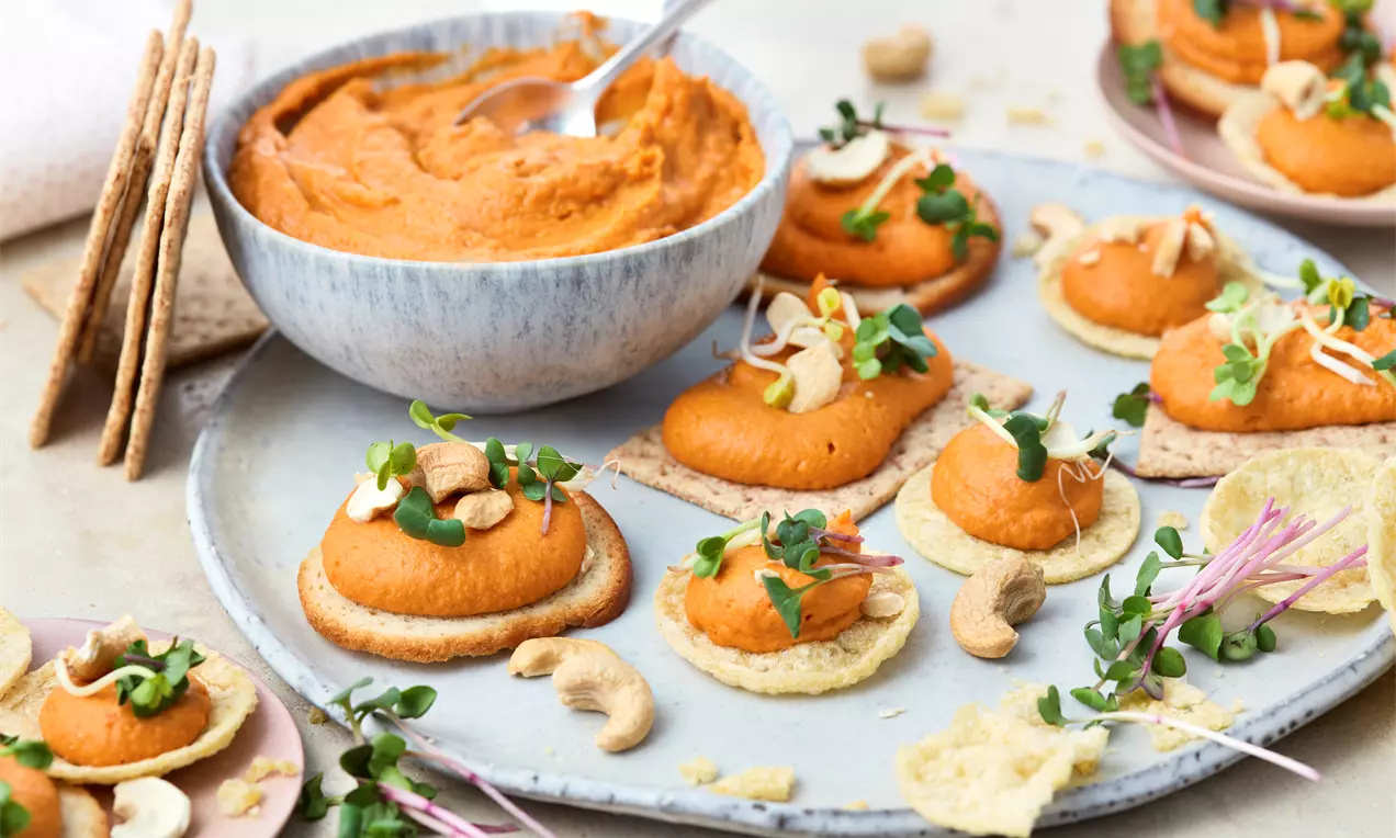 Knusprige vegane Cracker, serviert mit cremigem Paprika-Hummus – der perfekte Snack für zwischendurch, ideal als Fingerfood oder leichte Vorspeise für Genießer.