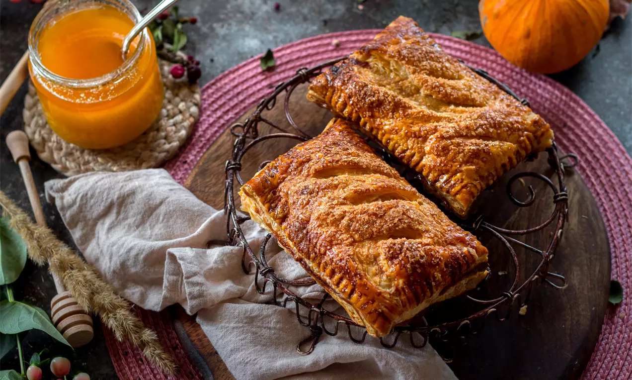 Златисто-кафяви правоъгълни пайове от бутер тесто с карамелизирана коричка и леки резки, подредени върху метална решетка върху дървен плот