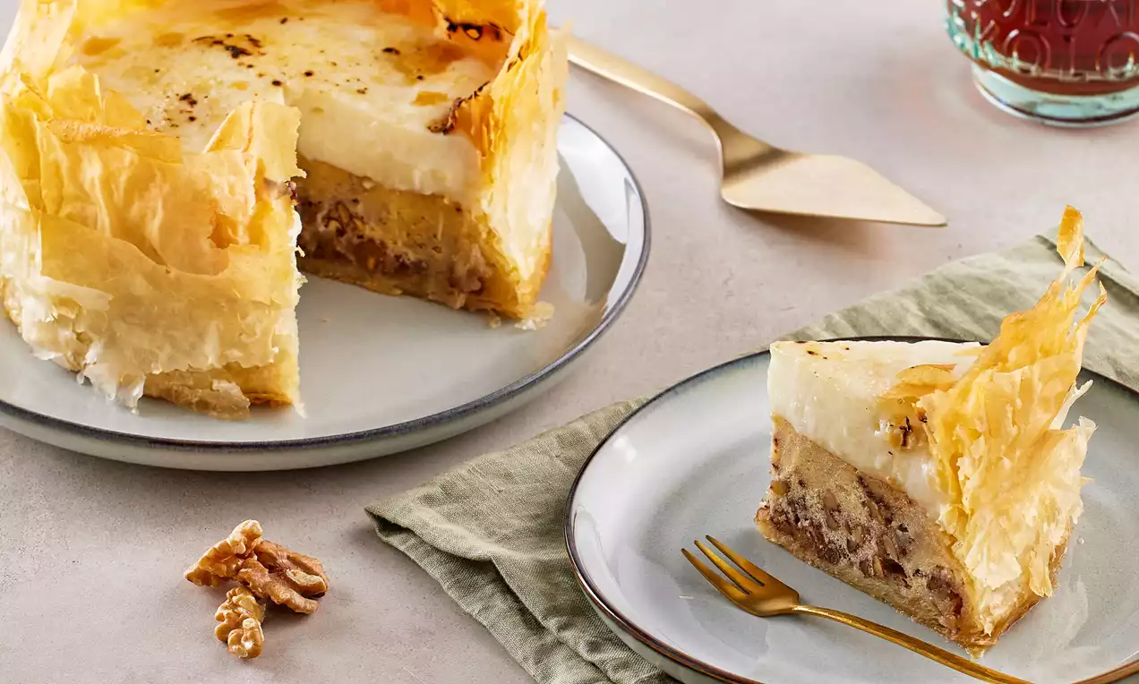 Kat kat çıtır hamurlar üzerinde ceviz parçalı dolgu ve kremsi beyaz üst katmanla dilimlenmiş, modern sunumla tabaklara yerleştirilmiş