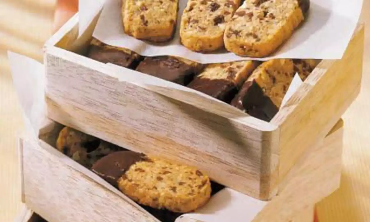 Rechteckige Schokoladen-Nuss-Plätzchen mit schokoladenüberzogenen Enden auf weißem Papier in gestapelten Holzkisten drapiert