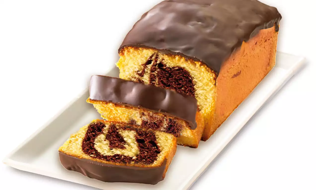 Cake marbré avec des tourbillons de chocolat et de vanille, recouvert d'un glaçage au chocolat brillant, présenté sur une assiette blanche