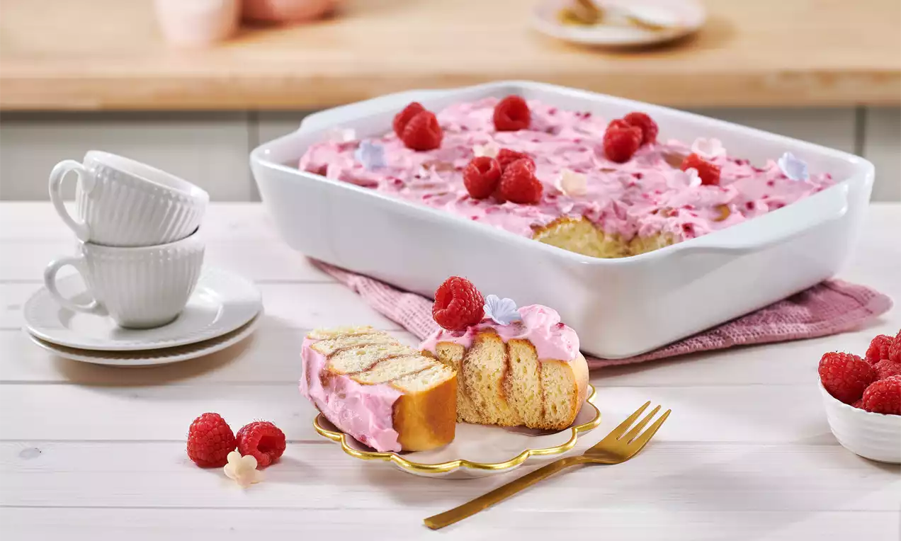 Himbeer-Schnecken mit lockerer Teigstruktur, bedeckt von cremiger rosafarbener Himbeerfüllung, garniert mit frischen Himbeeren auf einem goldenen Teller
