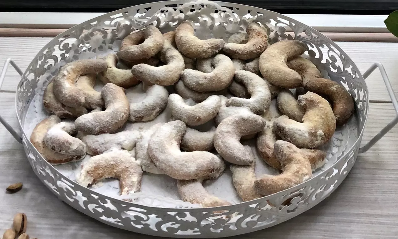 Ванилови кифлички със светлокафяв загар, извити като рога, поръсени с фина бяла захар, подредени върху ажурна метална табла