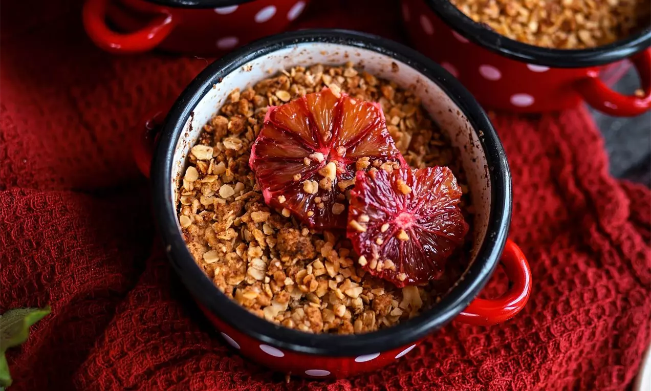 Miska so zapečeným crmble zdobená červeným pomarančom na červenom podklade