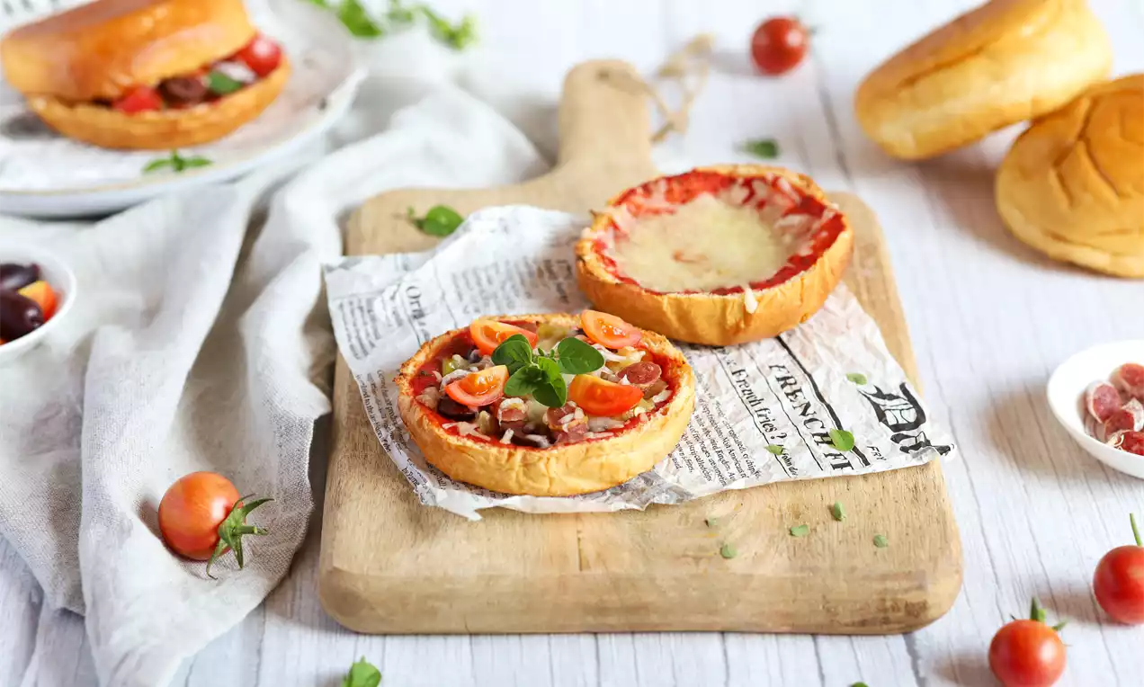 Pizza burger s hrskavom zlatnom pecivom, sočnim nadjevom od rajčice, sira, špeka i cherry rajčica, dekoriran svježim listićima bosiljka