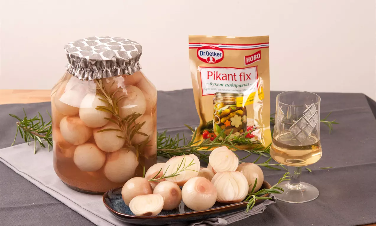 Цели бели лукчета с гладка, полирана текстура, в буркан с прозрачен саламура и стрък розмарин, подредени до чиния с разрязани лукчета