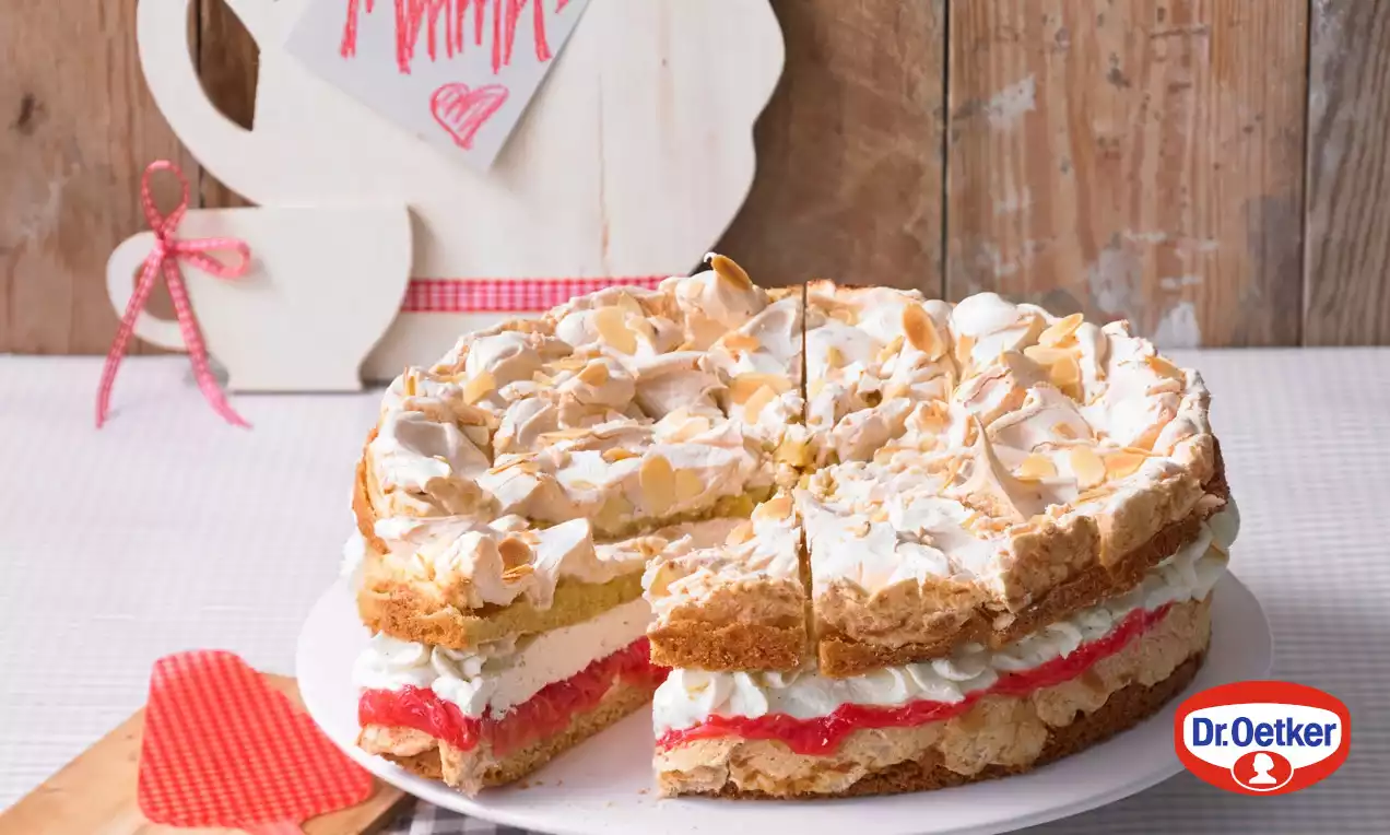 Sněhový dort se zlatavou křupavou horní vrstvou, bílým krémem, jasně červenou rebarborovou vrstvou, na bílém talíři na světlém podkladu