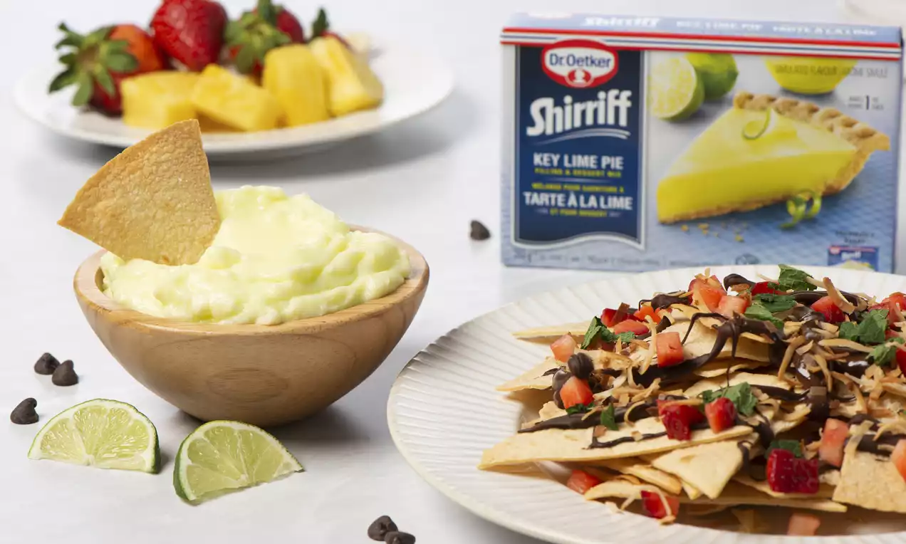 Chips dorées garnies de dés de fraises rouges, feuilles de menthe et filet de chocolat, accompagnées d'une crème lime onctueuse