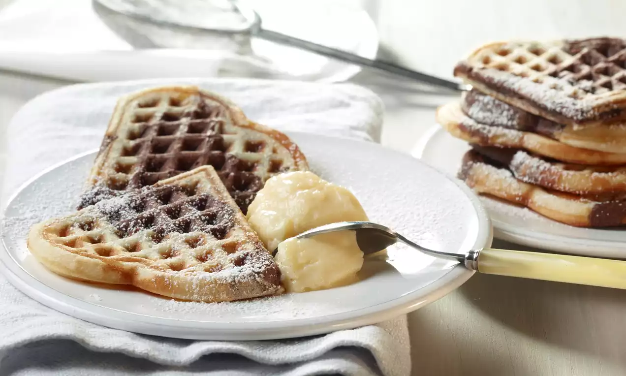 Marmorwaffeln mit schwarz-weißer Marmorierung und Kakaoswirlen, leicht mit Puderzucker bestäubt und auf einem weißen Teller gestapelt