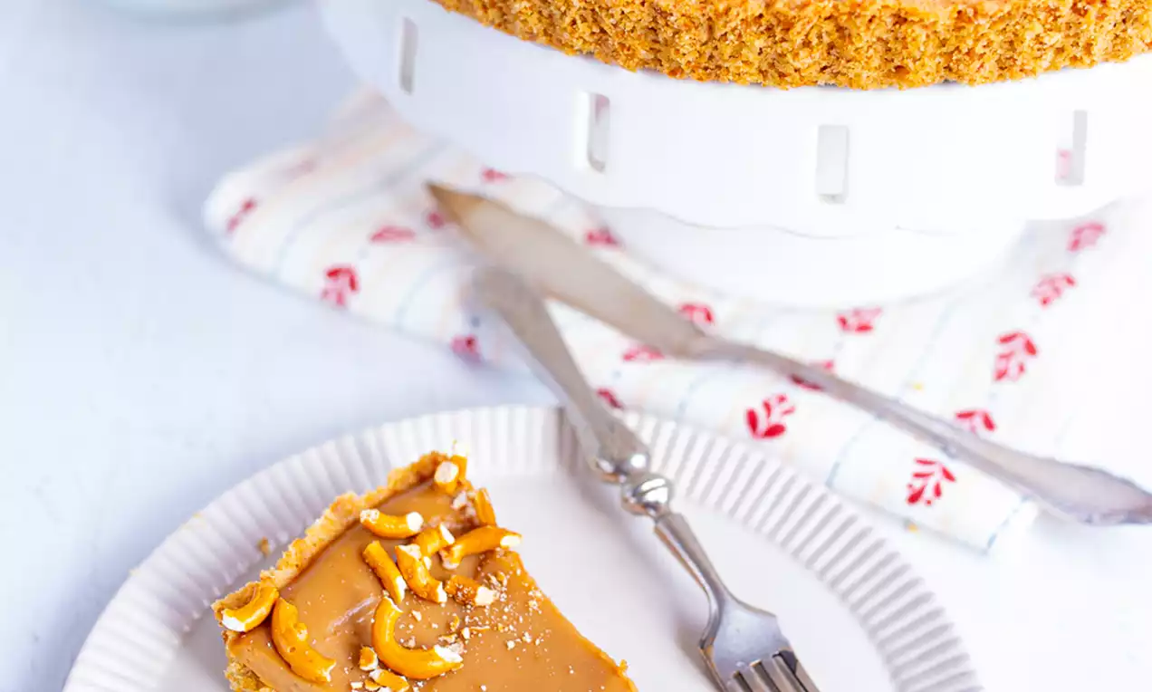 Perec tart sa svjetlosmeđom karamel kremom na hrskavoj podlozi, posut komadićima pereca i krupnom soli, na bijelom tanjiru