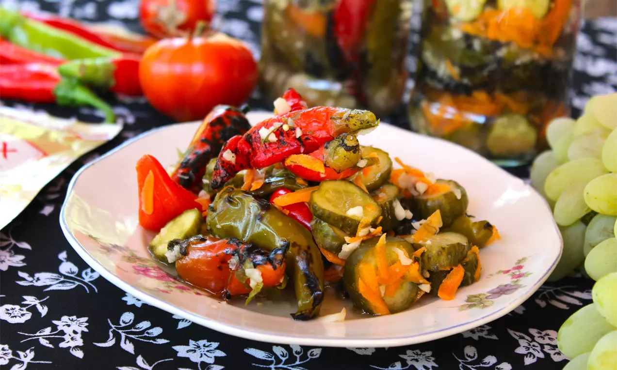 Пъстри пукани люти чушлета в яркочервено и зелено с крехки морковени и краставичени резенчета върху флорална чиния