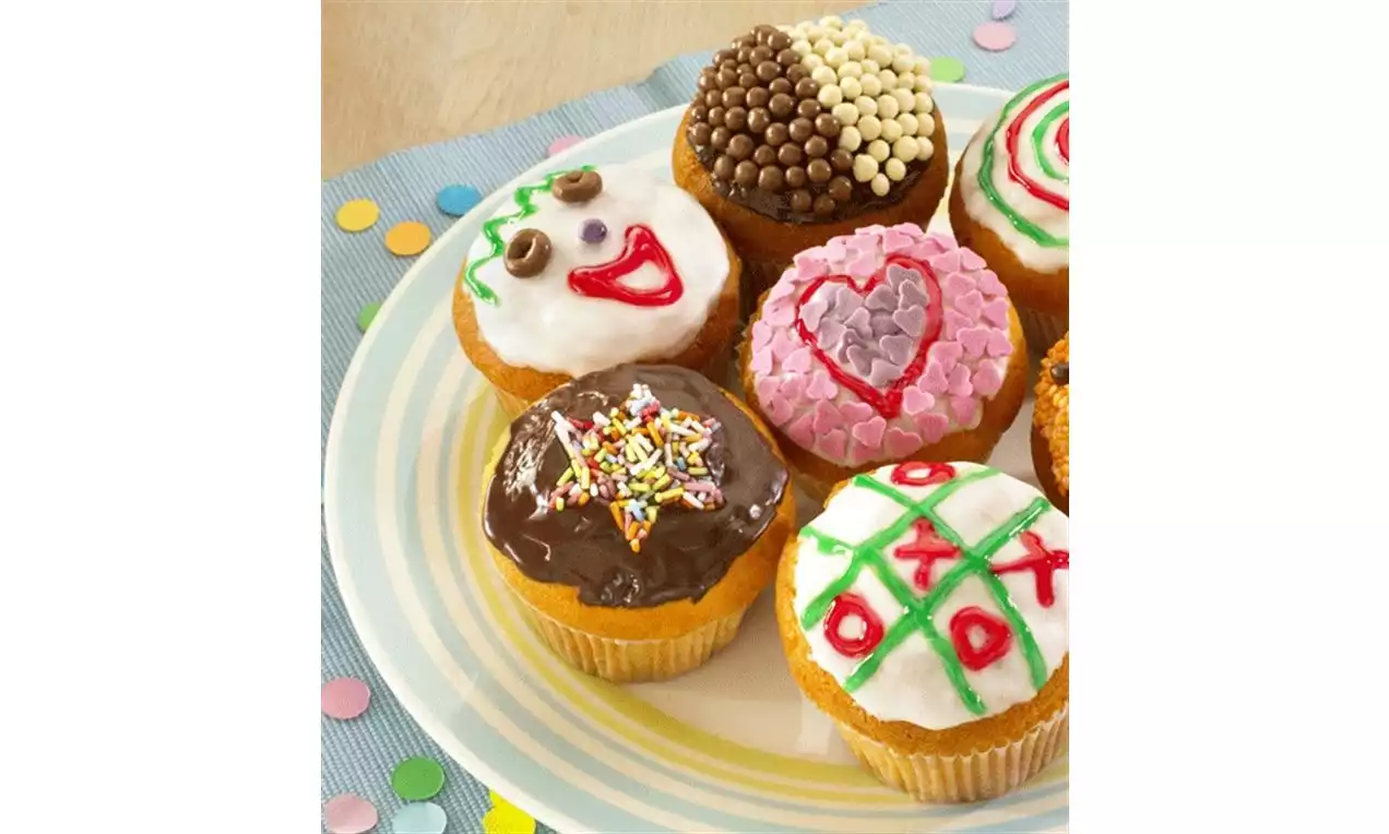 Cupcakes moelleux ornés de glaçages colorés, motifs variés et granulés, disposés sur une assiette à rayures pastel