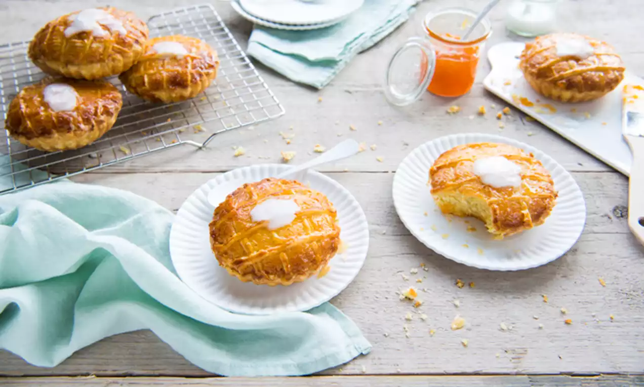 Zelfgemaakte, goudbruine rond gebakken taartjes met een glanzende suikerlaag en kruimels, geserveerd op witte borden met een lichtgroene doek
