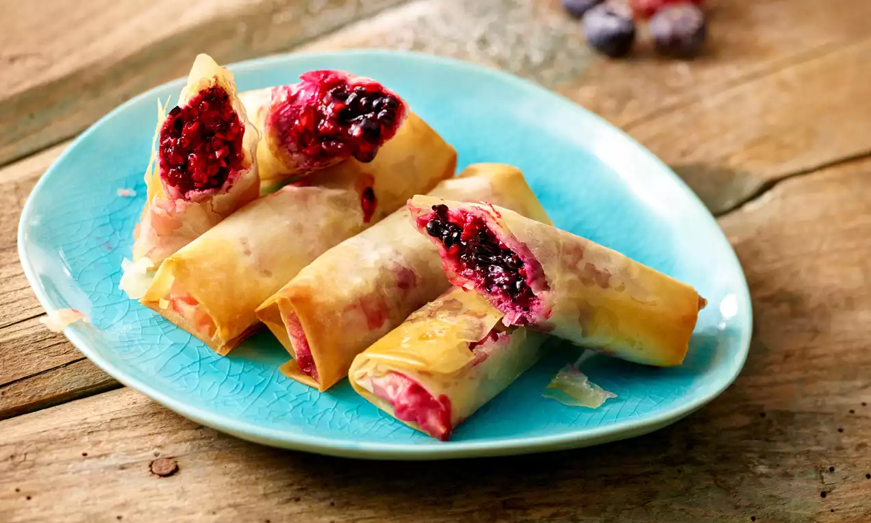 Knusprige Frühlingsrollen mit goldbrauner Hülle und fruchtig roter Füllung, angerichtet auf einem türkisfarbenen Teller