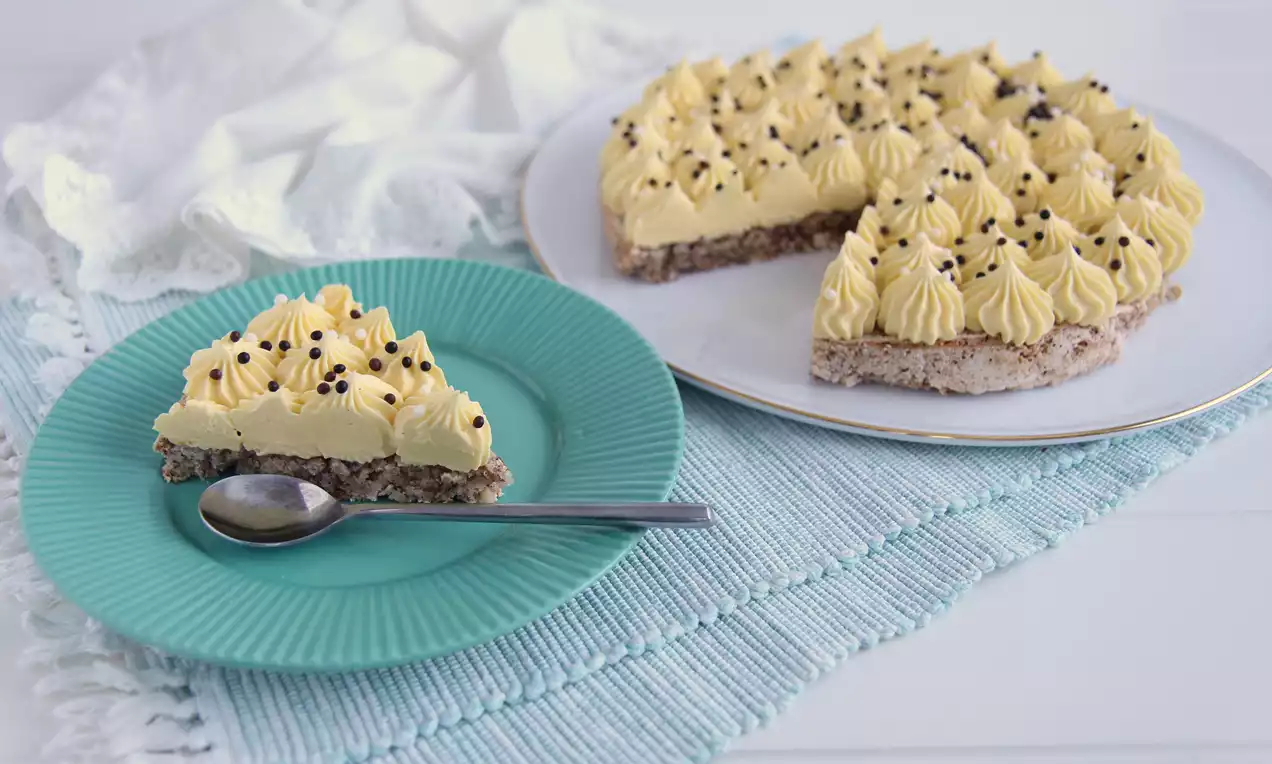 Gul krem toppet med sjokoladebiter i små rosetter på lys mandelbunn, servert på hvitt fat og grønn tallerken med skje ved siden av