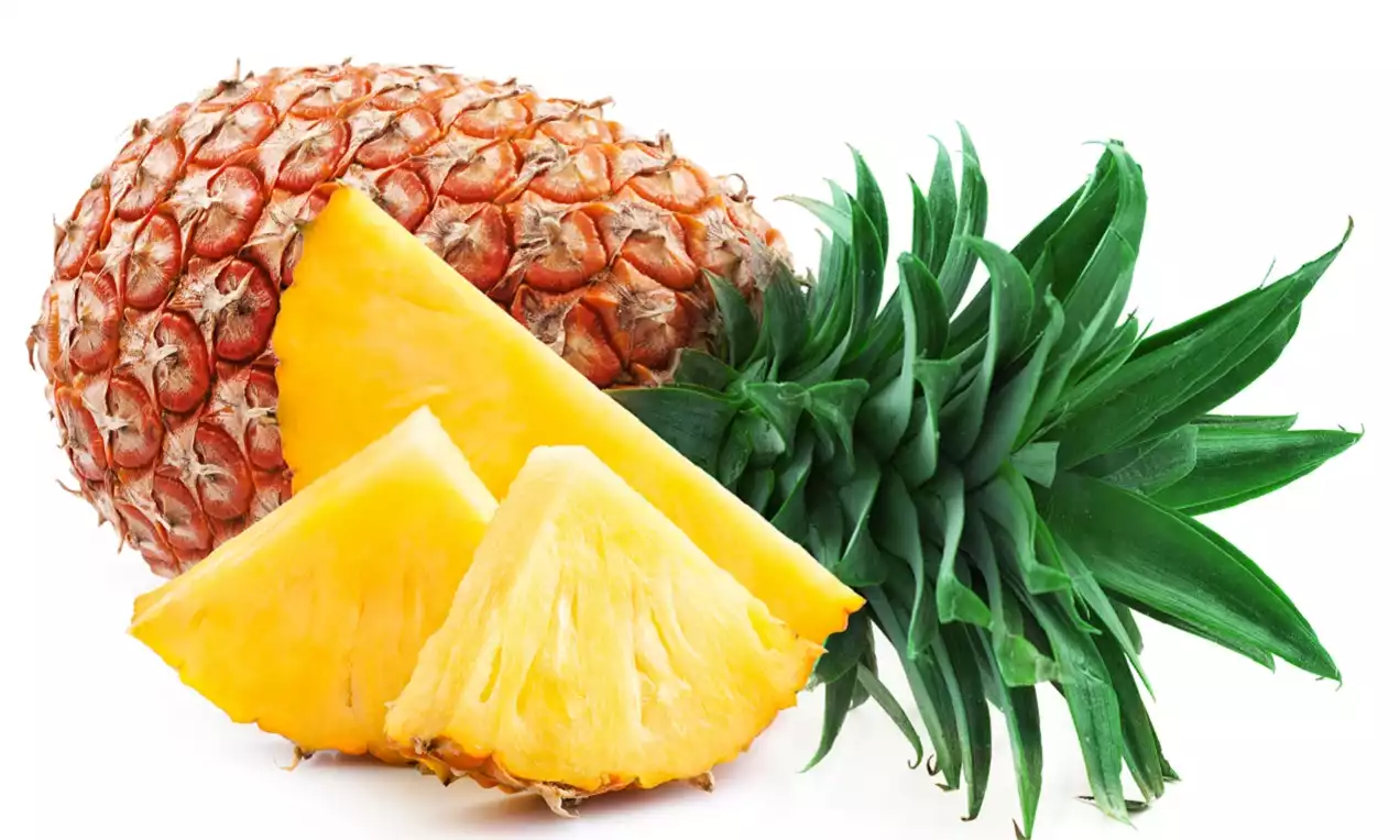Tam olgunlaşmış, dikenli kabuklu altın sarısı ananas, canlı yeşil yapraklarıyla birlikte ve özenle kesilmiş üçgen dilimleri yanında