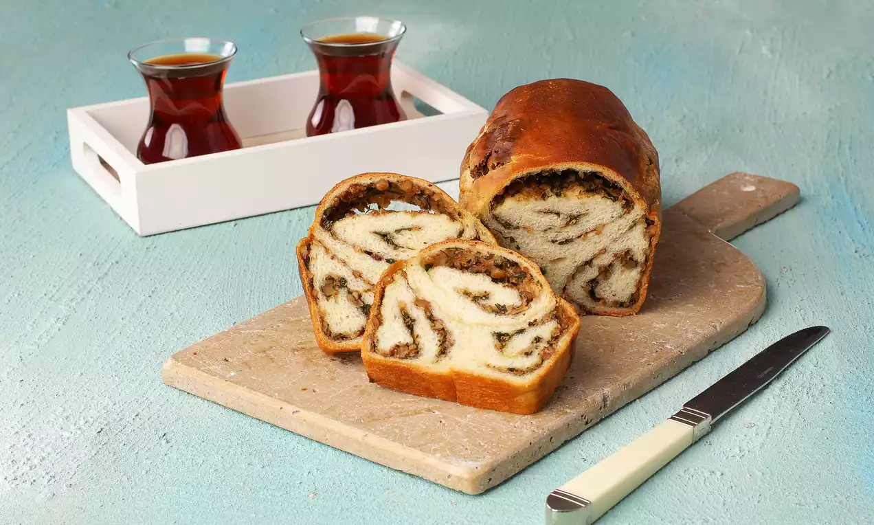 Cevizli ve soğanlı dolguyla hazırlanmış, altın rengi kabuğa sahip vegan çörek dilimleri ahşap kesme tahtasında servis edilmiş