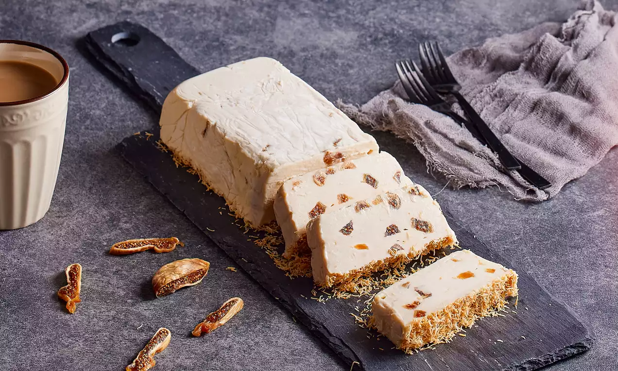 Dikdörtgen dilimlenmiş beyaz kestaneli parfe, altına serpilmiş tel kadayıfla birlikte siyah şık bir servis tahtasında sunulmuş