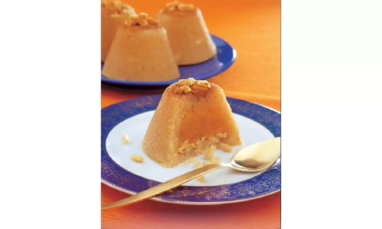 Tabağa ters çevrilerek konmuş, üzeri cevizle süslenmiş, içi dolgun ve yumuşak hünkâr helvası, beyaz tabakta altın kaşıkla sunulmuş