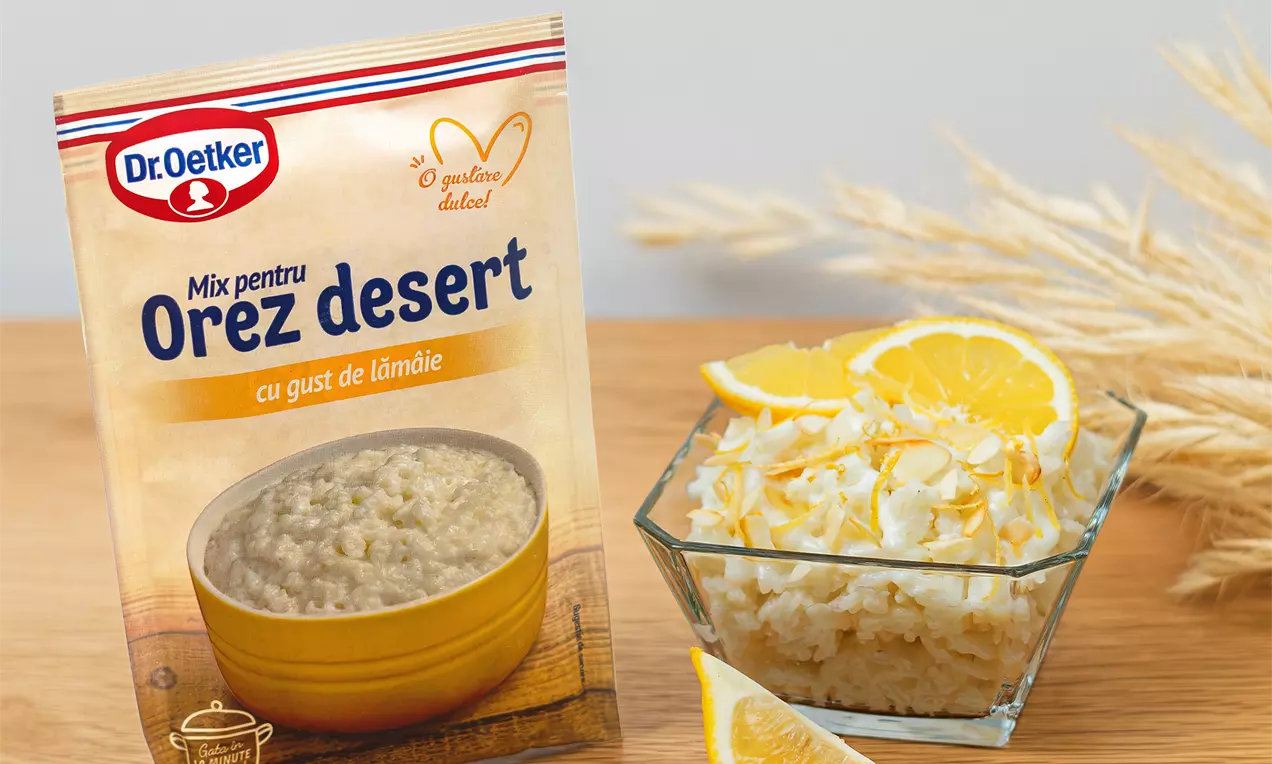 Orez alb cremos cu gust de lămâie, decorat cu felii de lămâie galben-strălucitor, aranjat într-un bol transparent pe un fundal de lemn