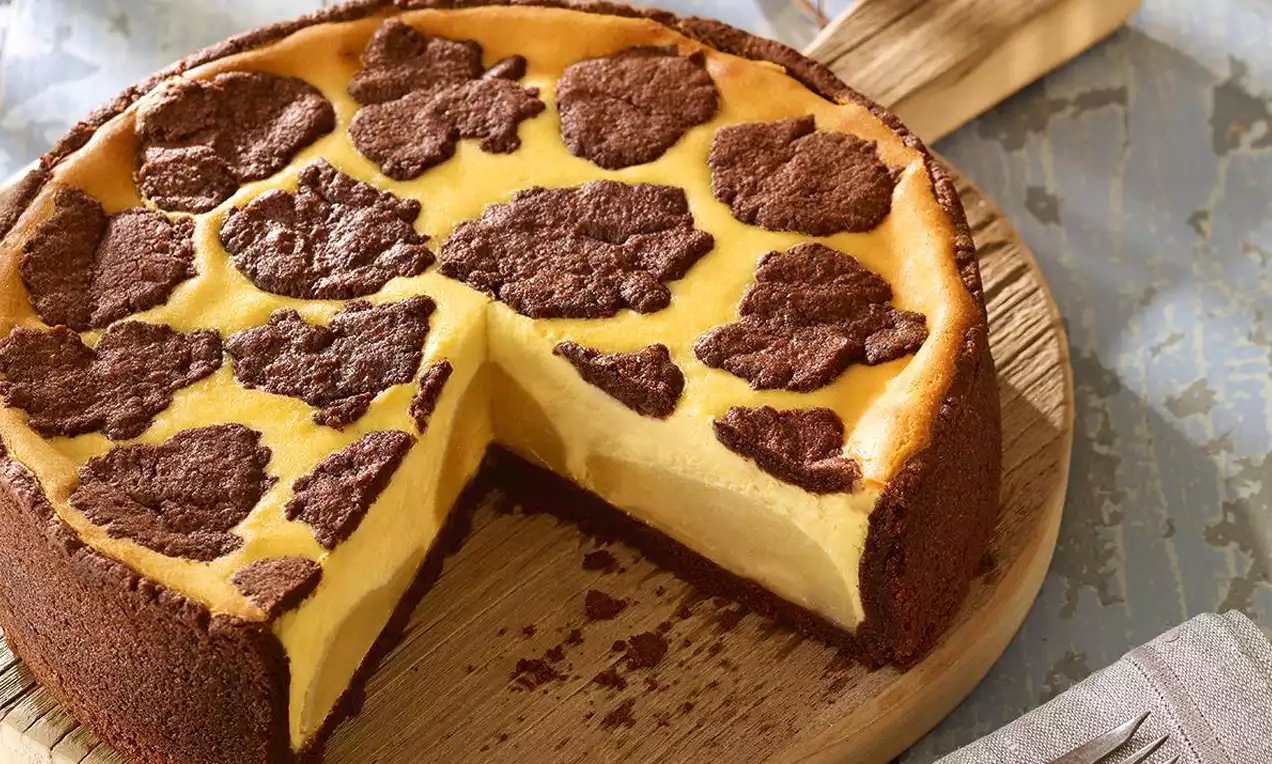 Čupavi kolač s kruškastom bazom od svijetlo smeđeg tijesta, pečenom kremom žute boje, prekriven tamnosmeđim prhkim komadićima.