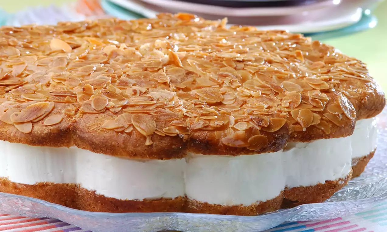 Bal peteği desenli bademli üst katmanı altın rengi, iç dolgusu beyaz kremalı ve kat kat görünümde cam tabakta sunulmuş tatlı.