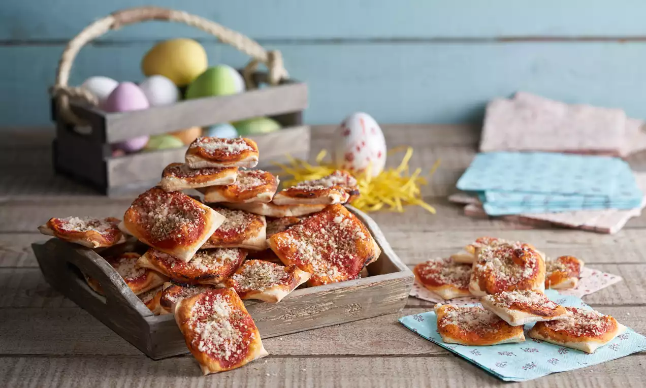 Petites pizzettes dorées et croustillantes garnies de sauce tomate et fromage, disposées dans une caissette en bois sur une table rustique