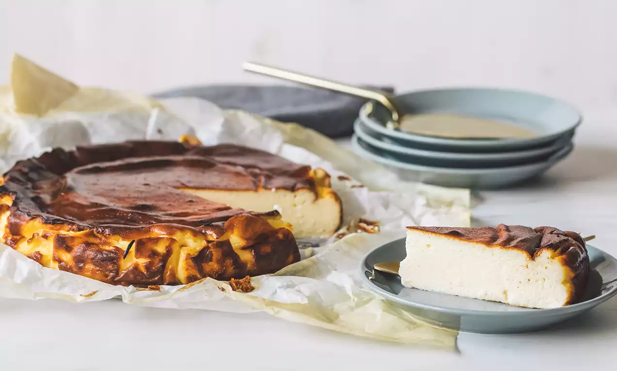 Tarta de queso San Sebastián con superficie dorada y caramelizada, interior cremoso y corteza irregular sobre papel de horno arrugado